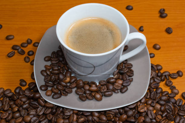 Turkish coffee- espresso coffee. Cloud and rain symbol made of coffee beans. White cup with coffee grounds inside. The concept of refreshing with coffee, waking up with coffee. Yellow background studio shot