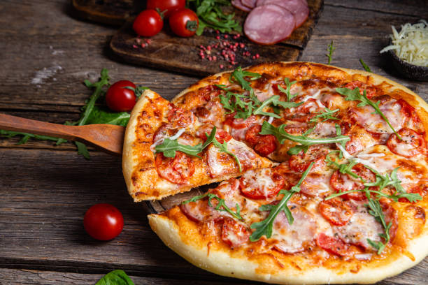 istock Appetizing pizza with ham on a wooden background 1480318184