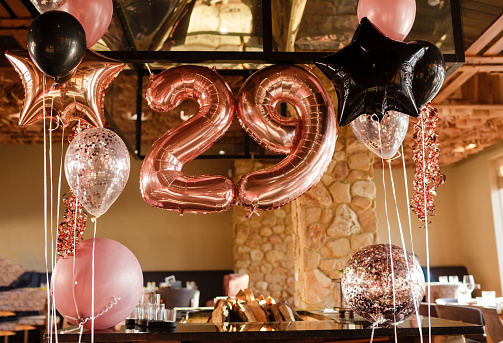 Restaurante room decorated for a birthday party with pink, black and transparent baloons of different sizes, large inflatable number 29. Photoshooting area