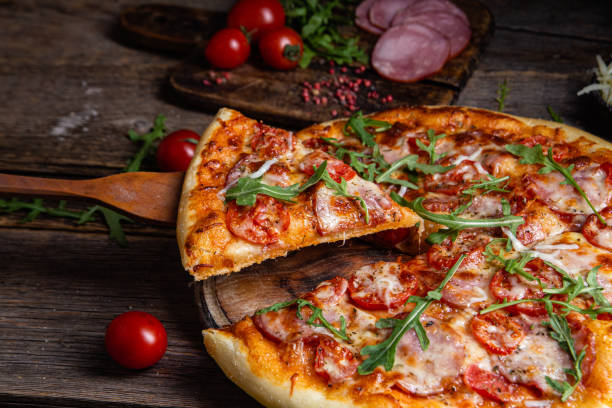 istock Appetizing pizza with ham on a wooden background 1480318840