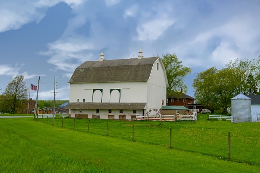 This image shows a summer landscape view of a rural 19th century wood constructed one-room country schoolhouse situated on a prairie in midwestern USA, with blue sky background.