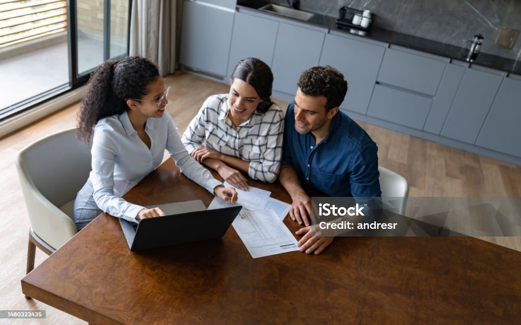 Financial advisor talking to a couple about their home finances Financial advisor talking to a Latin American couple about their home finances - business concepts Insurance Agent Stock Photo