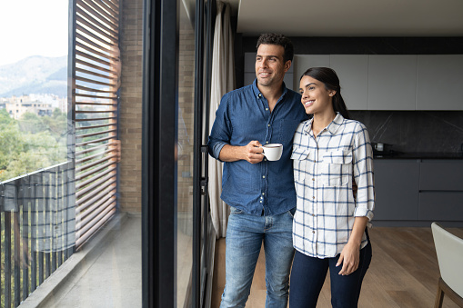 Loving couple relaxing at home drinking a cup of coffee and smiling - relationship concepts