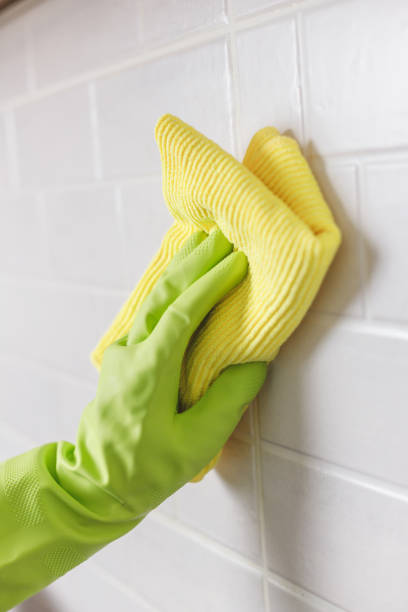 istock Hand in Gloves Washing White Tiled Wall in Kitchen with Yellow Microfiber and Spray Bottle with Detergent 1480324956