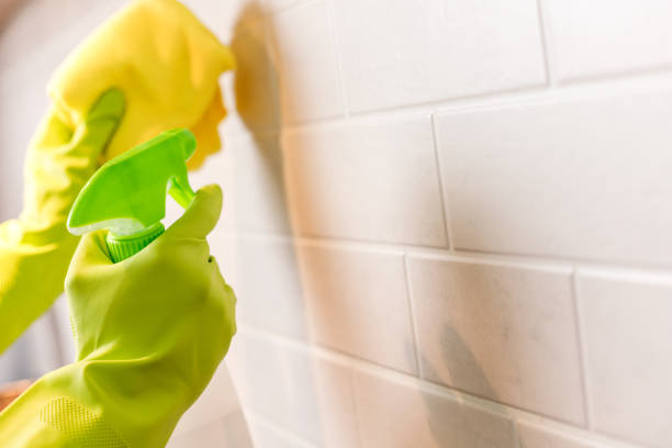 istock Hand in Gloves Washing White Tiled Wall in Kitchen with Yellow Microfiber and Spray Bottle with Detergent 1480324964