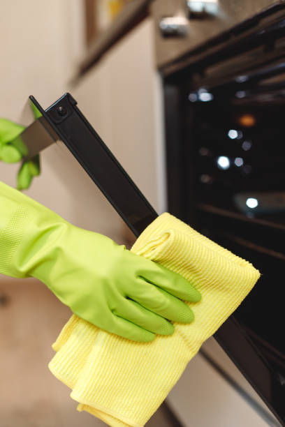 istock Hand in Green Glove Cleaning Kitchen Oven Door with Microfiber Rag. Doing Home Chores 1480329355