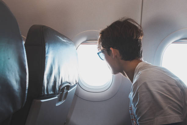 Young man embarks on his travels by means of an aircraft and observes the events below the plane. Air travel, expanding horizons stock photo
