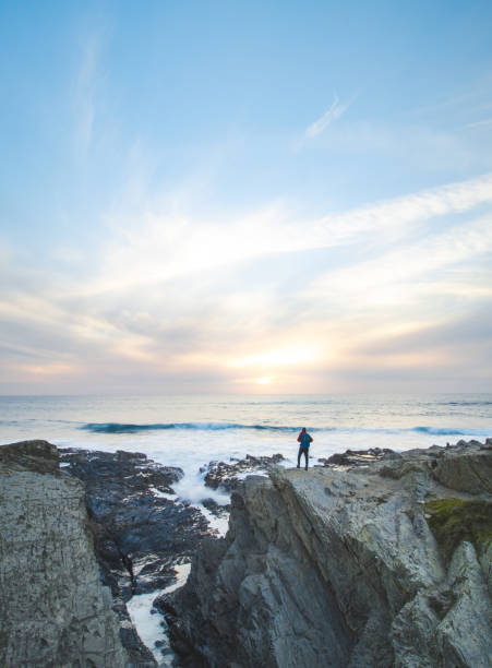 istock Fearless man with a backpack watching the sunset over the Atlantic Ocean in Porto Covo, Portugal. A hiker stands on the edge of a cliff looking into his future. Self-awareness 1480331104