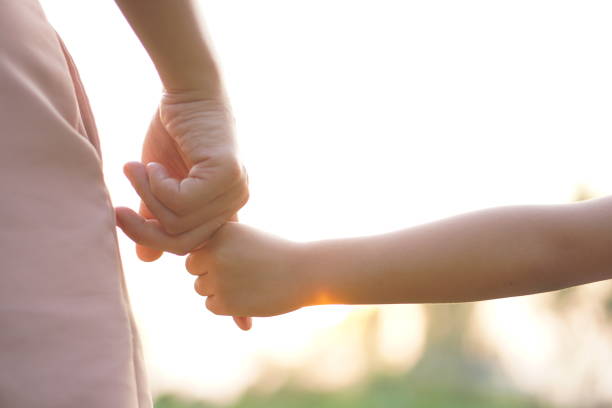 istock mother and child holding hands in sunset background 1480331323