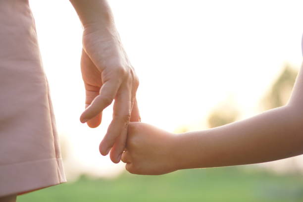 istock mother and child holding hands in sunset background 1480331324