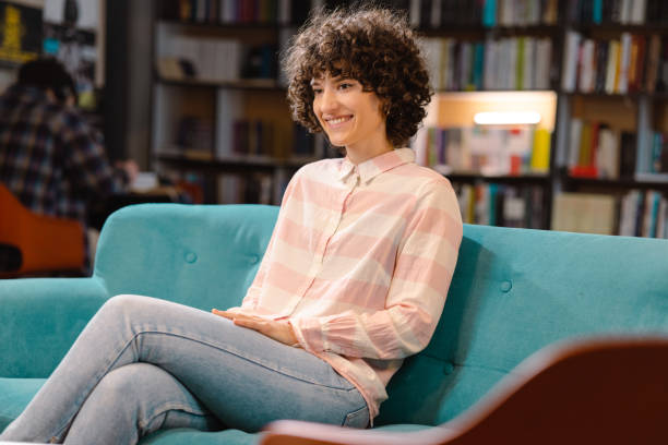 istock Young woman sitting on the sofa in the library 1480332254
