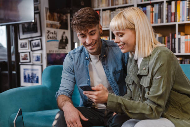 istock Friends using smart phone in the library and talking 1480332563