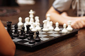 Teenager boy and little girl play chess