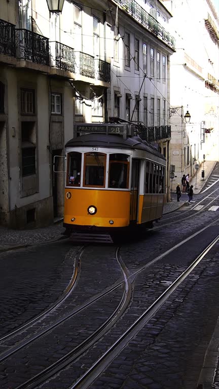 Iconic Yellow Tram 28 coming up the hill in Lisbon, Portugal