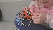 Cute Creative Caucasian Girl Trying to Untangle Hank Skein of Yarn