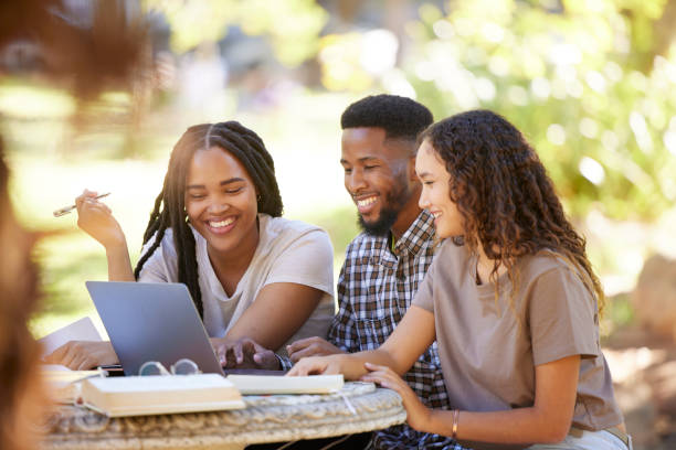 étudiants, amis et groupe étudiant avec un ordinateur portable au parc extérieur. bourse d’études, apprentissage du travail d’équipe et des gens heureux, hommes et femmes noirs avec un ordinateur pour la recherche à l’université ou au collège - étudiant en université photos et images de collection