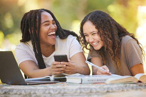 Students, friends and women with phone at park laughing at funny meme. University scholarship, comic and happy girls or females with mobile smartphone laugh at joke or crazy comedy on social media.