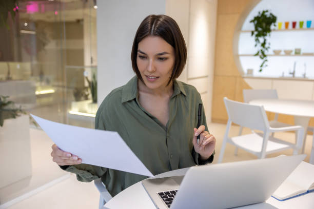 istock Focused female office worker looking through business documentation 1480345163