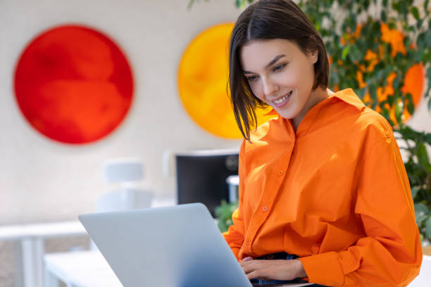 radosna pani pracująca na laptopie w nowoczesnym biurze - business district type zdjęcia i obrazy z banku zdjęć