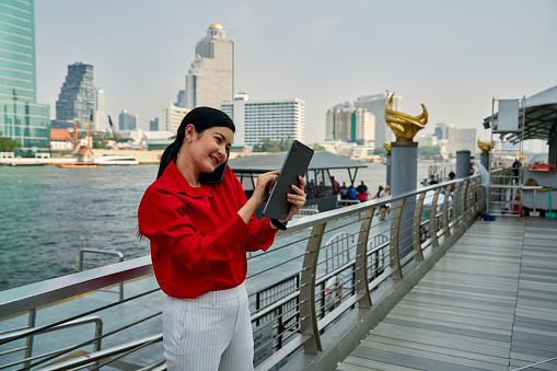 Asian Woman using digital tablet trade stock an online banking in the city