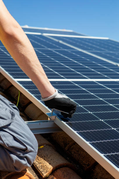 istock Close up of man technician in work gloves installing stand-alone photovoltaic solar panel system under beautiful blue sky with clouds. Concept of alternative energy and power sustainable 1480347140