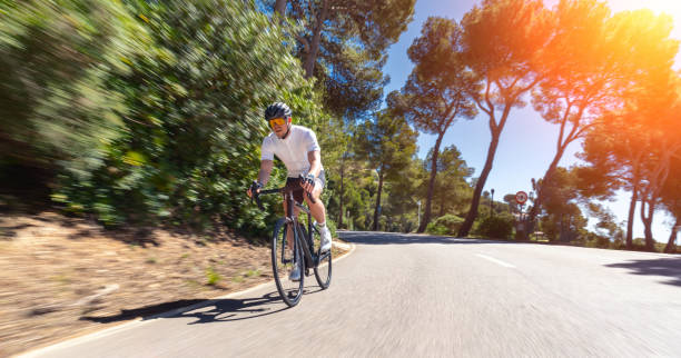 Man Adult on a racing bike climbing the hill at mediterranean sea landscape coastal road on mallorca balearic island stock photo
