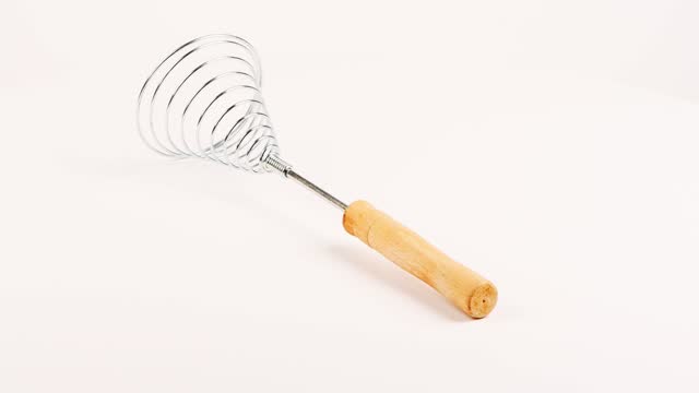 Сlose-up of old retro whisk kitchen tool on white background. Side view. Loop motion. Rotation 360.