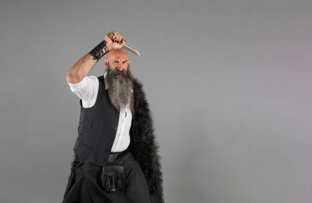 istock a bald bearded man with a fur in one shoulder holding a knife above his head 1480348111