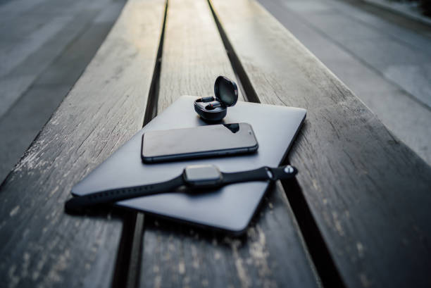 Black smartwatch, smartphone and wireless earphones on the grey pad