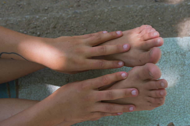 high angle view of a woman's foots and her hands touching her ankles | close up