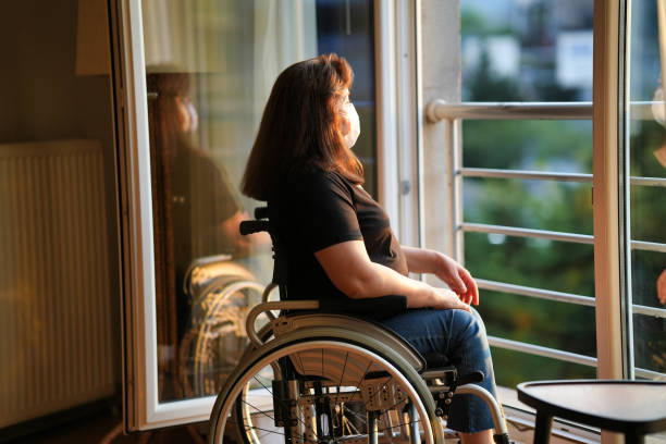istock Disabled woman in a mask looking out at the scenery 1480353352
