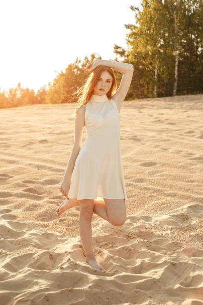 istock Redhead woman standing on sand at sunset 1480353743