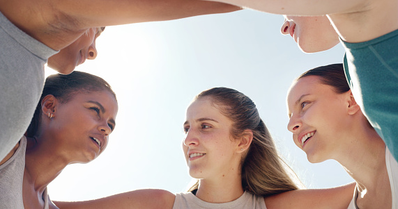 Face, huddle or team with a sports woman and friends standing in a circle together before a game. Fitness, exercise and teamwork with a female group training outside for a competitive sport event