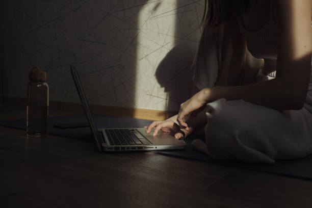 Crop female browsing laptop and choosing online yoga lesson during remote session at home
