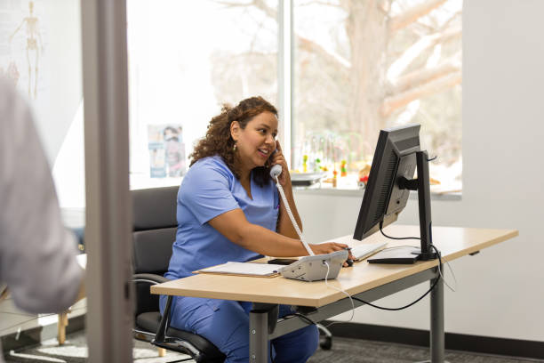 istock Nurse looks at information on computer while talking on phone 1480360605