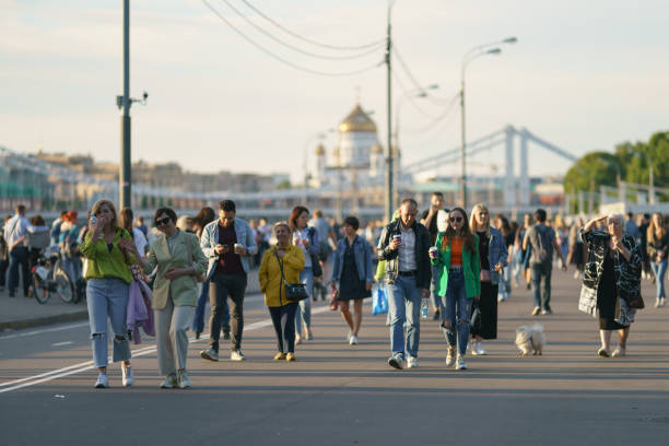 Moscow, Russia - June 4, 2021: People walk in public park in sunny summer day.Touristic and lifestyles concepts. Various generation and fashion stylies. Cathedral of Christ the Saviour in the distance