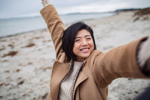 istock Young Asian woman taking a selfie on a beach 1480373716