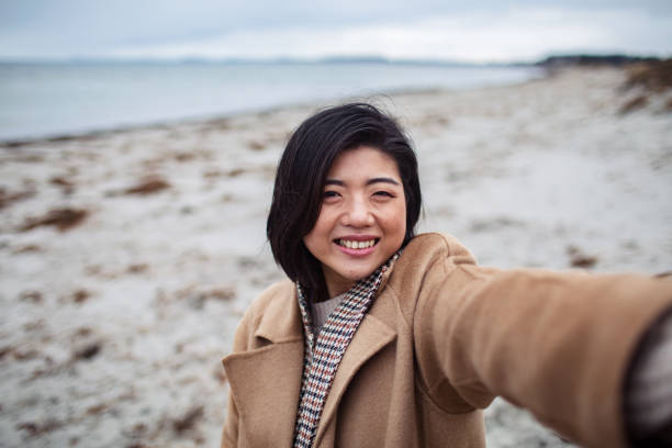 istock Young Asian woman taking a selfie on a beach 1480373727