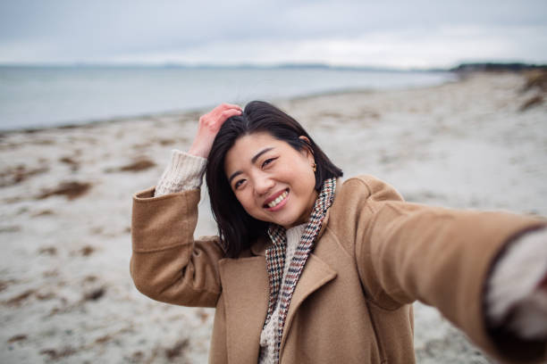 istock Young Asian woman taking a selfie on a beach 1480373882