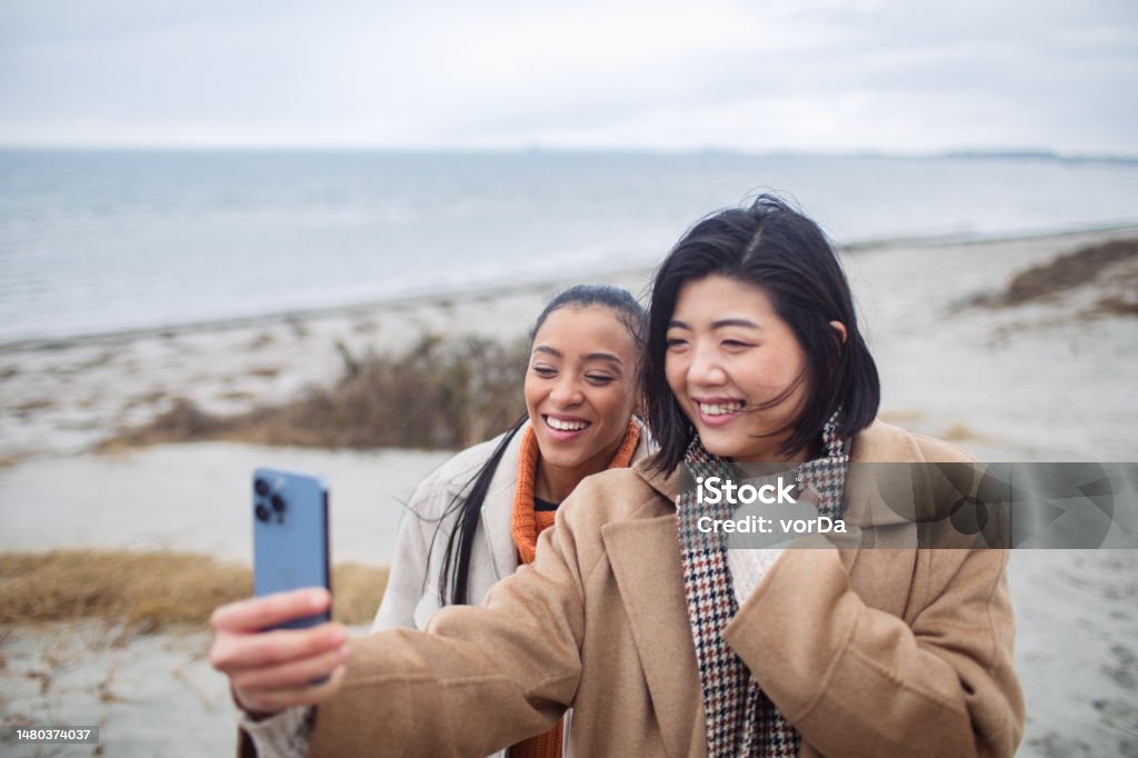 Two young women taking a selfie on a beach Close up of Two young women taking a selfie on a beach 20-29 Years Stock Photo