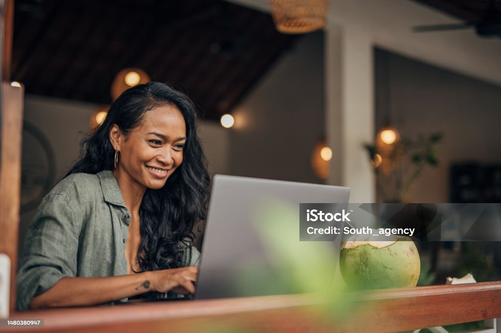 Modern woman using laptop One woman, beautiful female sitting in bar outdoors and using laptop. Laptop Stock Photo