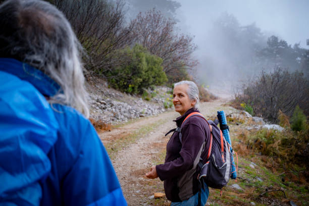 istock Elderly couple walking on forest soil forest path in fog. 1480388621