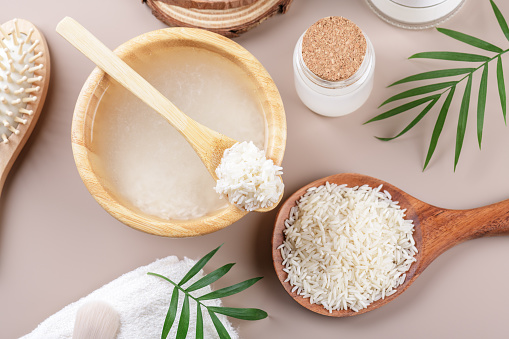 Homemade cosmetic rice water with ingredients on beige background, healthy beauty treatment ingredients for homemade comsetics, beauty recipe for home spa, natural skincare preparation, top view