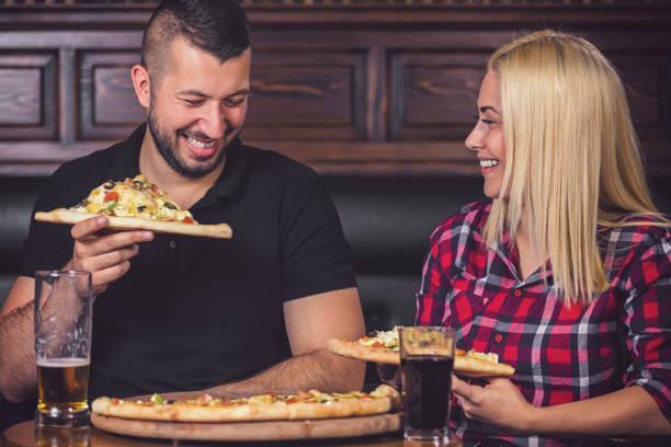 istock Young couple eating pizza and drinking beer in a pub 1480396906