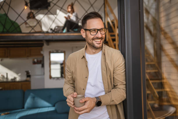 One adult man stand in at door of tiny house happy smile hold cup stock photo