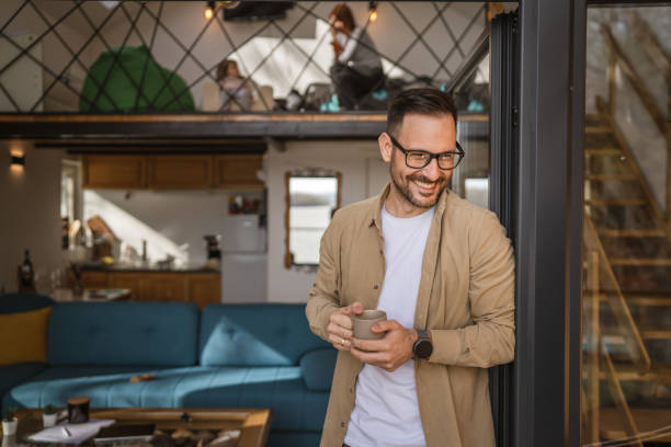 One adult man stand in at door of tiny house happy smile hold cup stock photo