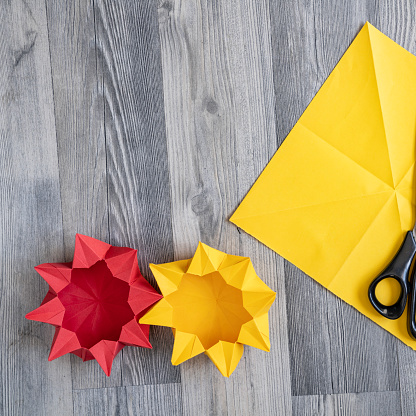 Photo of red and yellow colored origami figures on wooden surface. Shot from directly above.