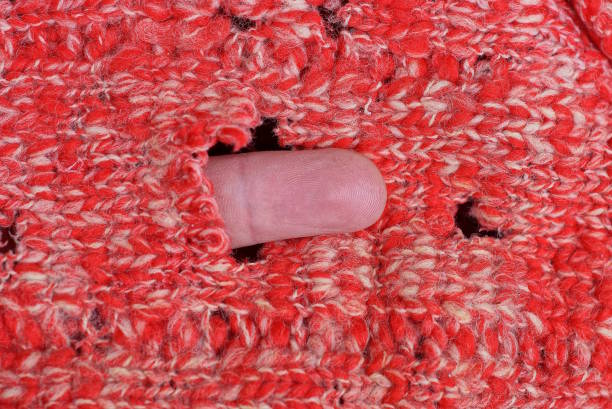 red white texture from an old woolen torn knitted fabric with  holes