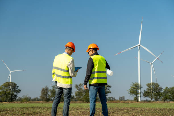 istock Windmills rotate in front of specialists standing on field 1480422525