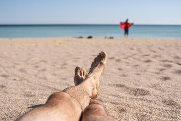 Feet on white sand on sunny day.